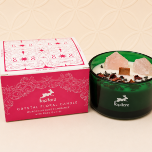 Hop Hare Crystal Magic Flower Candle The Lovers with Moroccan Rose fragrance, genuine Rose Quartz crystals, dried flowers and wooden wick in a deep green glass container beside its gift box.